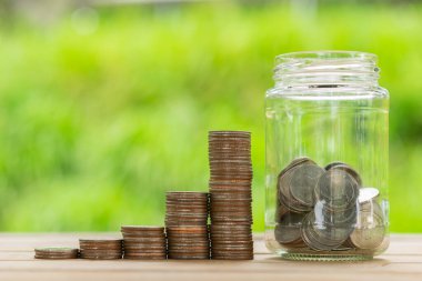 Bozuk para yığını, cam şişedeki yeşil bokeh arka plan. Bozuk parayı beyaz veya gri arkaplanda izole edilmiş olarak kavanoza kaydet. İş konsepti