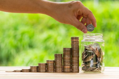 Beyaz adam kavanozu doldurmak için bozuk para ya da yeşil arka planda biriktirmek için cam şişe tutuyor. Para biriktirme, tasarruf kavramı