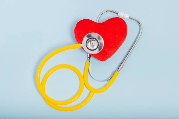 Red heart, Yellow Stethoscope on blue background with Copy space. Medical concept, Health care concept.