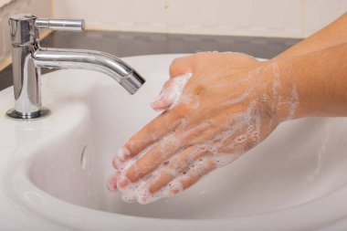 Erkek, Coronavirus 'u (COVID-19) önlemek için önce ve sonra ellerini sabunla yıkar..