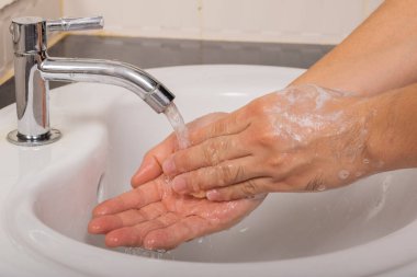 Erkek, Coronavirus 'u (COVID-19) önlemek için önce ve sonra ellerini sabunla yıkar..