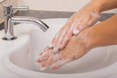 Erkek, Coronavirus 'u (COVID-19) önlemek için önce ve sonra ellerini sabunla yıkar..