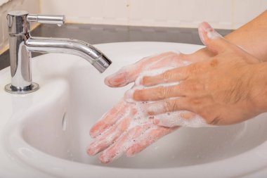 Erkek, Coronavirus 'u (COVID-19) önlemek için önce ve sonra ellerini sabunla yıkar..