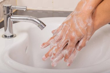 Erkek, Coronavirus 'u (COVID-19) önlemek için önce ve sonra ellerini sabunla yıkar..