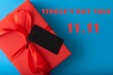11.11 single 'ın günlük satış konsepti. İnternetten alışveriş konsepti. Mavi arkaplanda siyah etiket kağıdıyla kırmızı hediye.