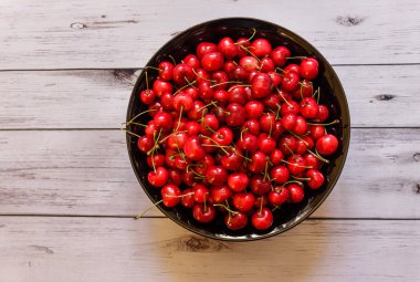 Beyaz ahşap zemin üzerinde siyah kupa taze olgun organik kiraz