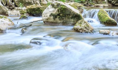 Güzel taş cascade ve moss ile kaplı büyük kayalar ile küçük şelale mahalline yakın çekim