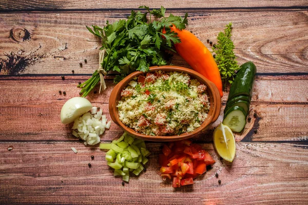Lezzetli ev yapımı vejetaryen kuskus ile domates, salatalık, biber, onoin, limon, maydanoz ve fesleğen ahşap arka plan üzerinde Kapat