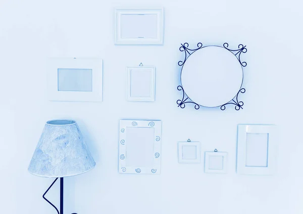 White wooden frames, mirror and lamp against white wall, close up