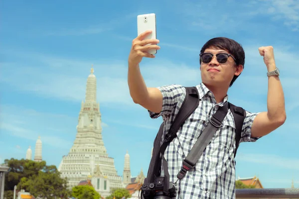 Turistas sosteniendo un teléfono móvil para tomar fotos sonriendo — Foto de Stock