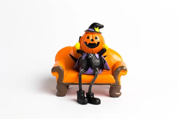 Zauberer Kürbis Halloween sitzt auf einem orangefarbenen Sofa. — Stockfoto