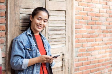 Bir ceket, kot pantolon ve turuncu gömlek giyen kız bir karşı duran