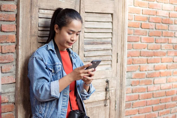 Meisje het dragen van een jas, jeans en oranje shirt staan tegen een — Stockfoto