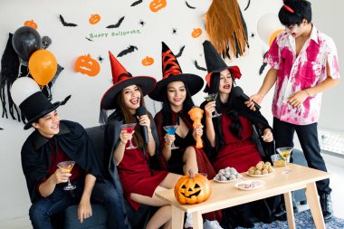 Kostüm giymiş genç Asyalı cadı çetesi, Cadılar Bayramı partisini kutlayan büyücü odada şarkı söyleyip içki içen büyücü. Gençler ve Taylandlılar Cadılar Bayramı 'nı kutluyor. Kavram partisi Cadılar Bayramı evde.