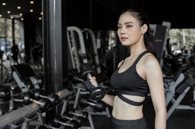 Salonda fotokopi odalı halterli Asyalı seksi kadınlar egzersizi. Dambılı kaldıran tatlı bir kadın. Jimnastik arka planında dambılı tutan Taylandlı kız. Spor salonundaki egzersiz kavramı.