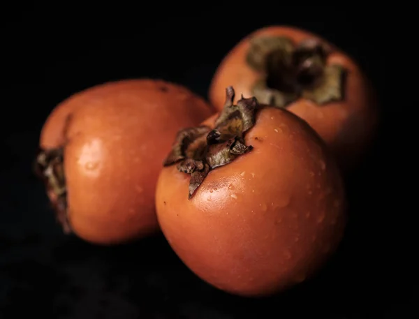Trzy persimmon Kaki izolowane na czarnym tle w całości — Zdjęcie stockowe