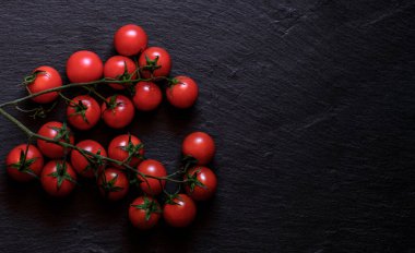 Siyah arka planda taze kiraz domatesleri. Kopyalama alanı olan üst görünüm