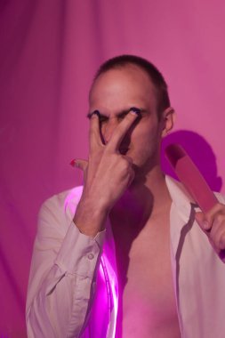 Düğmeleri iliklenmemiş beyaz gömlekli yakışıklı adamın portresi. Neon renkli oda. Eski 90 'lar eski moda. Erkeğe yakın neon kelimelerin yansıması.