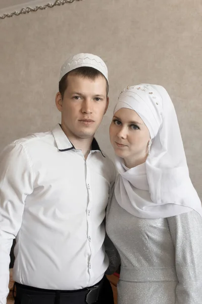 Couple young muslim man and women using smart phone contact with partner together in outdoor building city, Muslim tatar wedding. Man and woman in white dresses