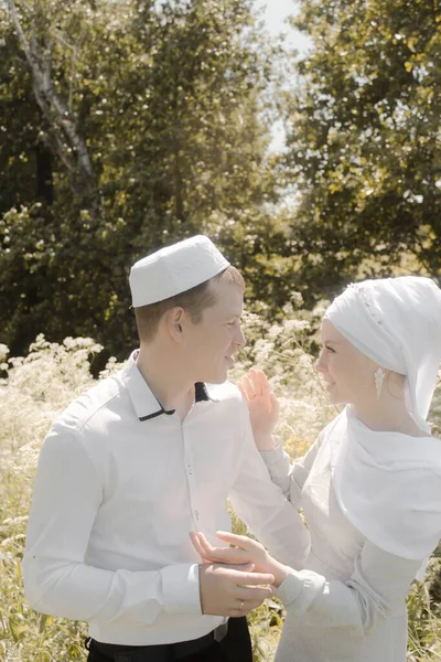 Couple young muslim man and woman on the summer field look to each other. Muslim tatar wedding.
