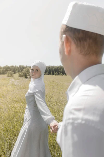 Yaz tarlasında iki genç müslüman erkek ve kadın birbirlerine bakıyorlar. Müslüman Tatar düğünü.
