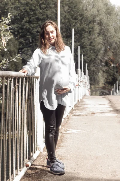 Nehir kenarında mutlu ve gururlu hamile bir kadının portresi.