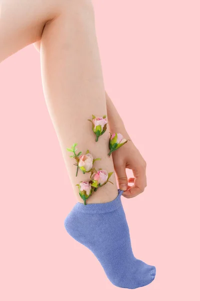 Pembe arka planda pembe çiçekleri olan ince tıraşsız bir kadın..