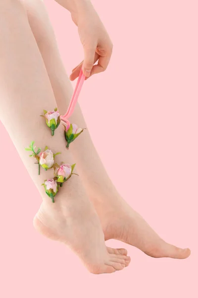 Pembe arka planda pembe çiçekleri olan ince tıraşsız kadınlar. Kadın bacağını pembe bir jiletle tıraş ediyor. Feminizm