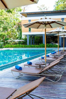Otelde ve tatil beldesinde yüzme havuzunda güzel şemsiye ve sandalye - tatil kavramı