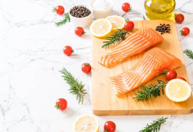 Limon domates Biberiye Biber ve tuz ahşap tahta üzerinde Çiğ somon fileto