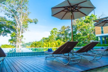 Otelde ve tatil beldesinde yüzme havuzunda güzel şemsiye ve sandalye - tatil kavramı