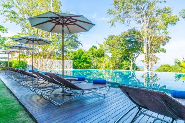 Otelde ve tatil beldesinde yüzme havuzunda güzel şemsiye ve sandalye - tatil kavramı