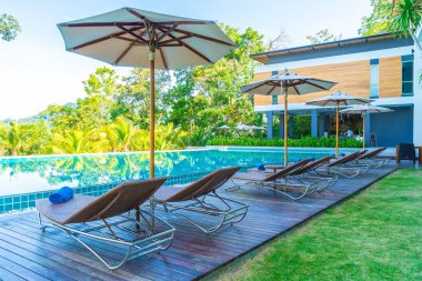 Otelde ve tatil beldesinde yüzme havuzunda güzel şemsiye ve sandalye - tatil kavramı