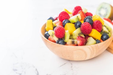 Ahşap kasede taze meyveler (çilek, ahududu, yabanmersini, kivi, mango)