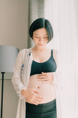 Genç güzel Asyalı hamile kadın ona dokunan karın evde - vintage filtre stili ile seçici odak noktası
