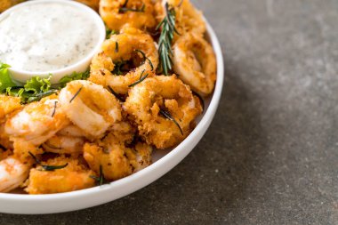 Tahta üzerinde sos olan kızarmış deniz ürünleri (mürekkep balıkları, karidesler, midyeler)