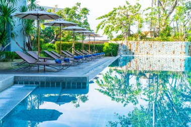 Otelde ve tatil beldesinde yüzme havuzunda güzel şemsiye ve sandalye - tatil kavramı
