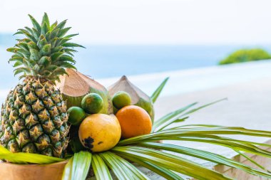 tropikal meyve (ananas, portakal, mango, limon, Hindistan cevizi) deniz arka plan ile karıştırın