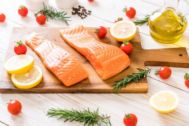 Limon domates Biberiye Biber ve tuz ahşap tahta üzerinde Çiğ somon fileto