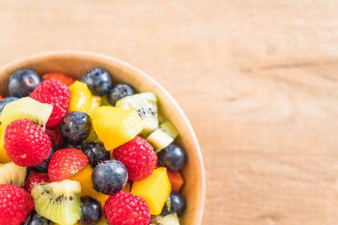 Ahşap kasede taze meyveler (çilek, ahududu, yabanmersini, kivi, mango)