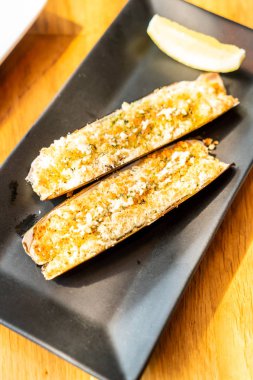 Ustura plaka üzerinde Ekmek kırıntı ve kızarmış sarımsak tereyağı ile süslenmiş istiridye