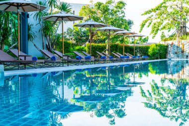 Otelde ve tatil beldesinde yüzme havuzunda güzel şemsiye ve sandalye - tatil kavramı