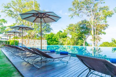 Otelde ve tatil beldesinde yüzme havuzunda güzel şemsiye ve sandalye - tatil kavramı