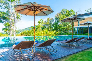 Otelde ve tatil beldesinde yüzme havuzunda güzel şemsiye ve sandalye - tatil kavramı