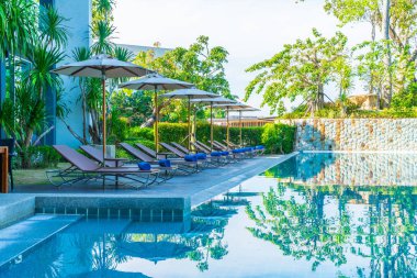 Otelde ve tatil beldesinde yüzme havuzunda güzel şemsiye ve sandalye - tatil kavramı