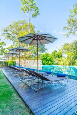 Otelde ve tatil beldesinde yüzme havuzunda güzel şemsiye ve sandalye - tatil kavramı