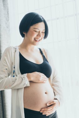 Genç güzel Asyalı hamile kadın ona dokunan karın evde - vintage filtre stili ile seçici odak noktası