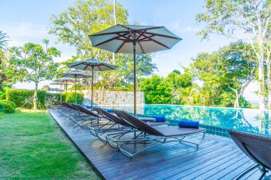 Otelde ve tatil beldesinde yüzme havuzunda güzel şemsiye ve sandalye - tatil kavramı