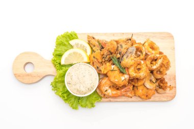 Beyaz arka plan üzerinde izole soslu kızarmış deniz ürünleri (mürekkep, karides, midye)
