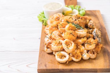 Tahta üzerinde sos olan kızarmış deniz ürünleri (mürekkep balıkları, karidesler, midyeler)